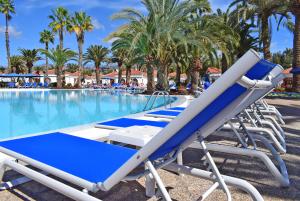 a row of lounge chairs next to a swimming pool at eó Suite Hotel Jardin Dorado in Maspalomas