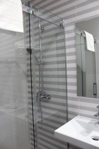 a shower with a glass door next to a sink at Hotel Altiana in Ourense