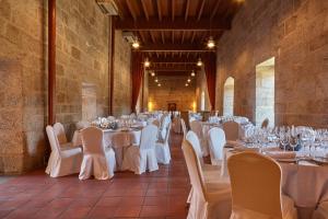 Un salón de banquetes con mesas y sillas blancas. en Eurostars Monumento Monasterio de San Clodio Hotel, en Leiro