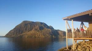 eine Gruppe von Menschen, die auf einem Deck stehen und auf einen Berg blicken in der Unterkunft Værlandet Havhotell in Hamna