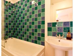 a bathroom with a green and blue tiled wall at Sand Dune in Looe