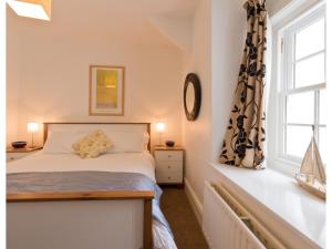 a bedroom with a bed and a window at Sand Dune in Looe