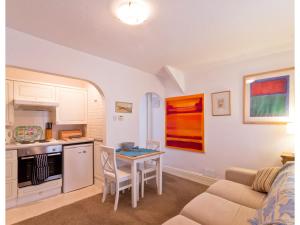 a kitchen and living room with a table and a couch at Sand Dune in Looe