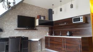 cocina con armarios de madera y TV en la pared en Apartament 30 Angel - Pod Aniołem, en Kazimierz Dolny