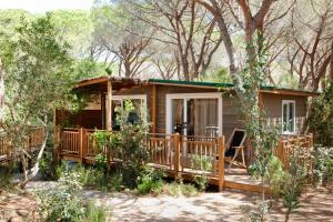 een hut in het bos met een veranda bij Camping Maremma Sans Souci in Castiglione della Pescaia