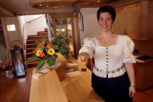 a woman is standing next to a table with flowers at Landhotel Hoisl-Bräu in Penzberg