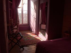 アングレームにあるHôtel du Palaisのベッド、窓、椅子が備わる客室です。