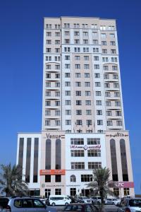 un edificio blanco alto con coches estacionados frente a él en The Venue Resident, en Kuwait