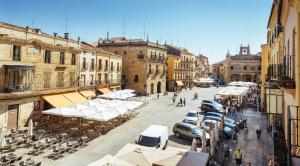 a city street with cars and tables and white umbrellas at Hospedería Castilla Plaza Mayor in Ciudad-Rodrigo