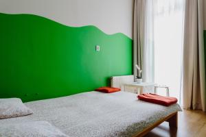 a green room with a bed with a green wall at Hostel Tara in Krakow