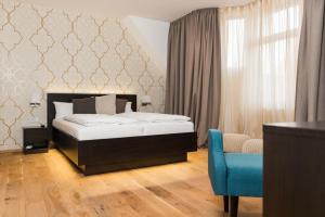 sypialnia z łóżkiem i niebieskim krzesłem w obiekcie The Heidelberg Exzellenz Hotel w mieście Heidelberg