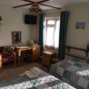 1 Schlafzimmer mit 2 Betten, einem Schreibtisch und einem Fenster in der Unterkunft Lower Thornton Farm in Exeter