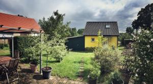 a backyard with a yellow house and trees at Gästehaus A+C Bovet in Wesenberg