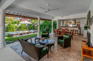 a living room with chairs and tables and a kitchen at Hevea Villas in Seminyak