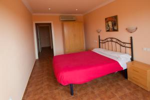 a bedroom with a large bed with a red blanket at Apartamentos Turisticos Aureus Bahia Sur in La Línea de la Concepción +8 photos