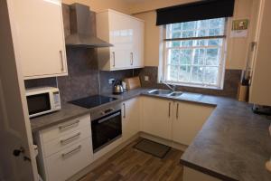 a small kitchen with white cabinets and a microwave at Elibank House Apartment in Walkerburn