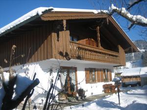 a log cabin with a balcony in the snow at Gästehaus Proisl in Lenggries