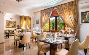 un comedor con mesas, sillas y ventanas en Hivernage Secret Suites & Garden, en Marrakech