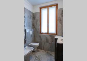 a bathroom with a toilet and a sink and a window at Appartamento vista Lago - Mary in Lezzeno +21 photos