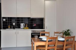 a kitchen with white cabinets and a table with chairs at Prudentia Apartments Jana Kazimierza in Warsaw