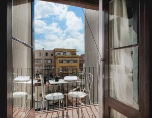 einen Balkon mit einem Tisch und Stühlen sowie einem Fenster in der Unterkunft Brummell Apartments Gracia in Barcelona