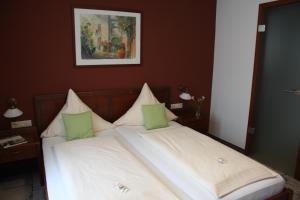 a bedroom with a bed with white sheets and green pillows at Hotel-Restaurant 1735 in Speyer