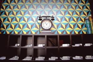 a clock sitting on a shelf in front of a wall at Flóra Panzió in Miskolctapolca