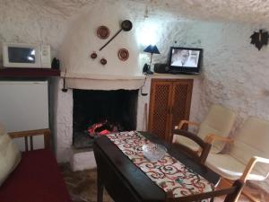 Cueva El Madrono في Pegalajar: غرفة معيشة بها موقد وطاولة وكراسي