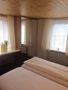 a bedroom with two beds and two windows at Hotel Restaurant Heidihof in Maienfeld