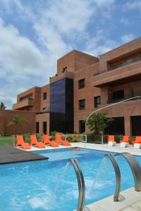 a swimming pool with orange chairs and a building at Neper Hotel in Córdoba