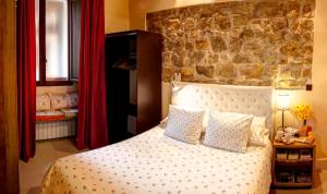 1 dormitorio con cama y pared de piedra en Casa Rural Siguenza Domus 200m2 de Vivienda y Exterior, en Sigüenza