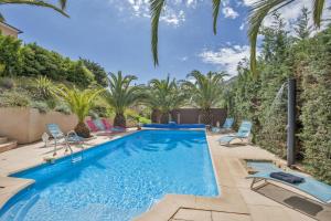 a pool with chairs and palm trees in a backyard at Gites Carolina in Sisco