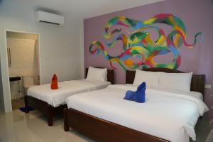 two beds in a room with a painting on the wall at Lanta Smile Beach in Ko Lanta