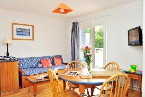 uma sala de estar com um sofá azul e uma mesa em Goélia Résidence du Golf de l'Océan em Carantec