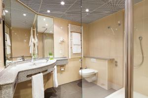 a bathroom with a toilet and a sink and a shower at Hotel du Parc Baden in Baden