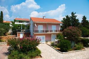 a house with a balcony and some bushes at Apartman Nikodem in Novalja