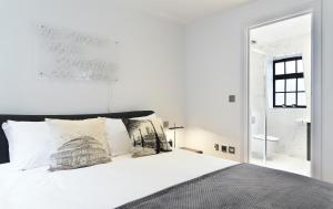 a bedroom with a white bed and a mirror at Veeve - Marylebone Mews in London