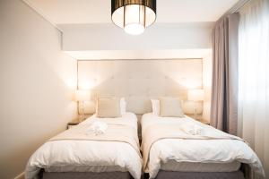 two beds in a bedroom with white sheets at Waters Edge Self-Catering Apartment in Cape Town