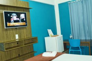 a room with a bed and a tv and a blue wall at Bonjour Hotel in Macaé
