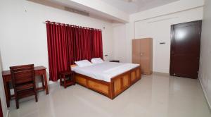 a bedroom with a bed and a red curtain at Indeevaram Residency in Trivandrum