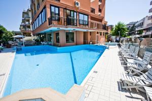 a swimming pool with chairs and a building at Hotel Apollo in Cesenatico