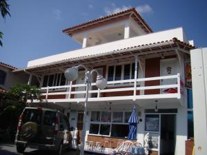a white building with a table and chairs in front of it at Pousada do Nei in Cabo Frio