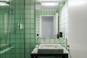 a green tiled bathroom with a sink and a mirror at Brummell Apartments Eixample Derecha/Ballroom in Barcelona