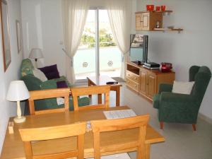 - un salon avec une table, des chaises et une télévision dans l'établissement Reception La Rotonda Aparthotel, à Playas de Orihuela