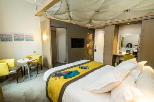 a bedroom with a large bed with a yellow blanket at Best Western Hôtel d'Arc in Orléans