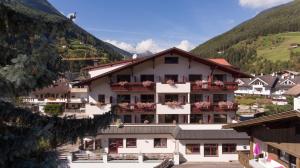 a large white building with flowers on the windows at Hotel Hellweger in Campo Tures