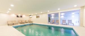 a pool in a room with chairs and a table at Hotel Hellweger in Campo Tures