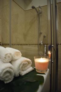 een badkamer met handdoeken, een kaars en een douche bij Cento Tari' Guest House in Castiglione di Sicilia
