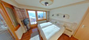 1 dormitorio con 1 cama, TV y ventanas en Les Petits Mélèzes, en Crans-Montana
