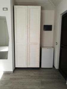 Zimmer mit zwei weißen Türen und einem Kühlschrank in der Unterkunft IRON GATE MARINA3B in Sarzana